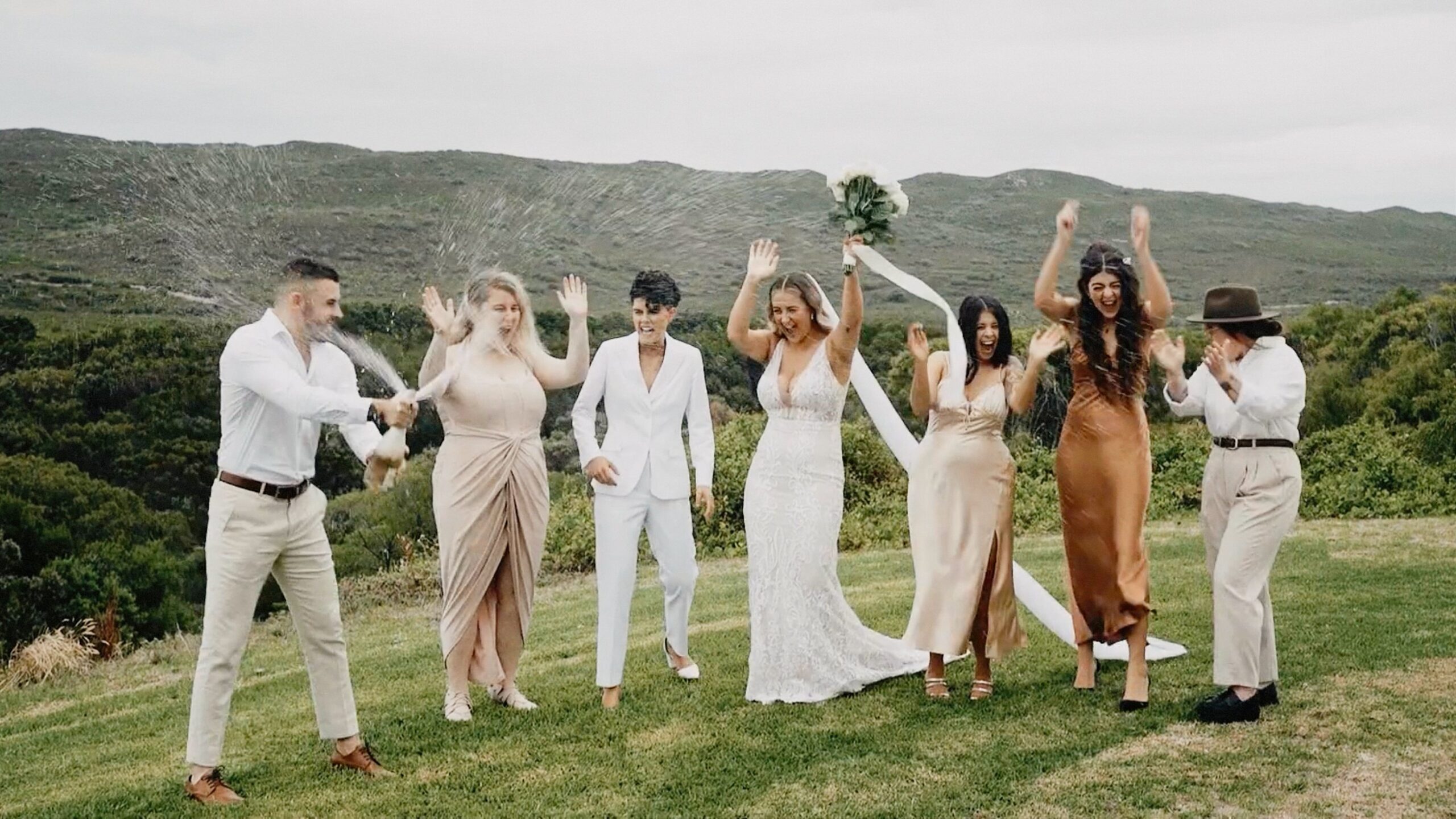 Jesse and Renae celebrating with champagne and their bridal party at Parry Beach Breaks in Denmark WA